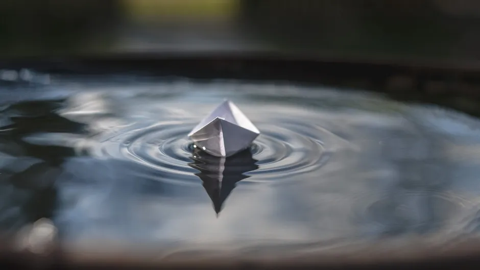 Blick auf ein fragiles Papierschiffchen auf dem Wasser